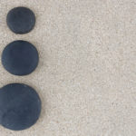 三个黑色的禅石在左侧的沙背景