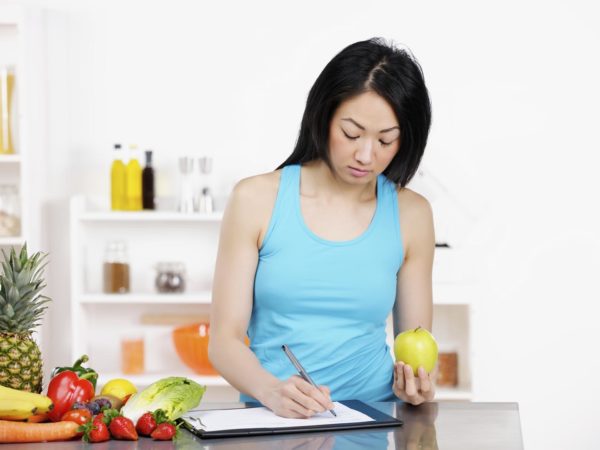 亚洲女性营养师记录饮食计划。