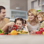 幸福的家庭在厨房里拿着健康的食物。