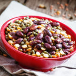 混合豆类:紫色的豆子，绿色和红色的扁豆，红碗里的干豌豆，古色古香的木制背景，选择性聚焦