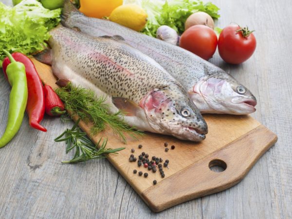 新鲜的鳟鱼，蔬菜和香料放在砧板上