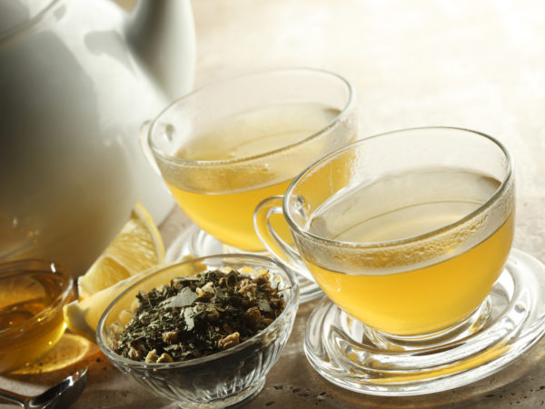 两杯茶。茶壶、蜂蜜、柠檬和杯子旁边的散茶。