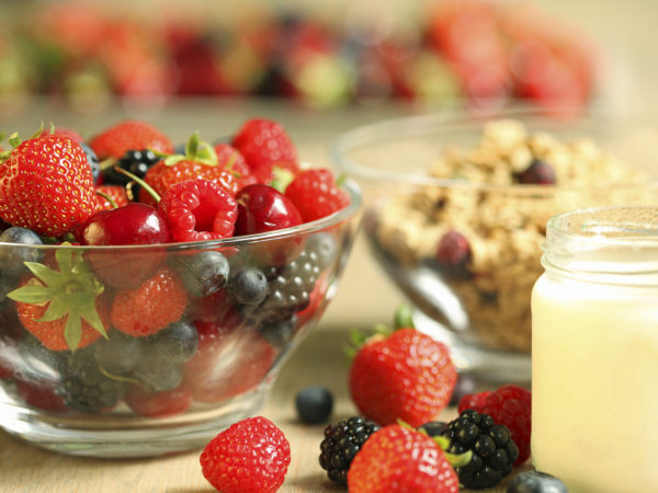 健康的早餐包括一小罐自制酸奶，一碗格兰诺拉麦片和各种新鲜的夏季浆果水果，如草莓，蓝莓，覆盆子，黑莓和樱桃。