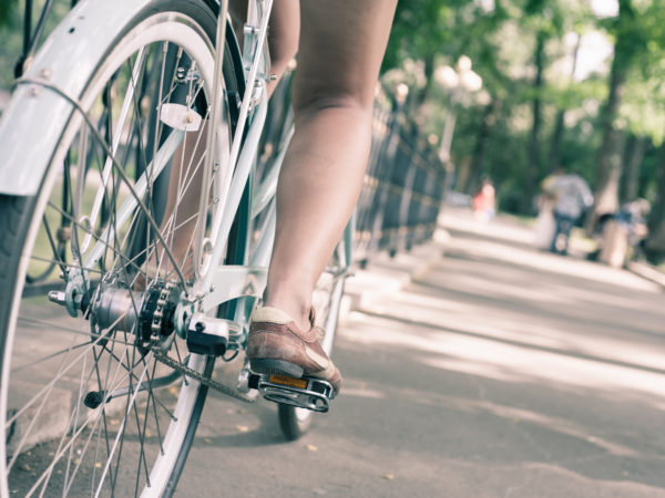 特写女人骑着蓝色的老式城市自行车在市中心。它就像活动、健康生活方式和环保交通的概念