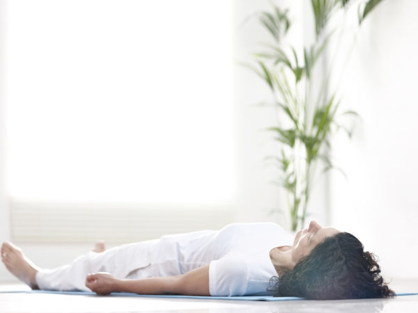 成熟女子躺在瑜伽垫上，放松后锻炼- Savasana