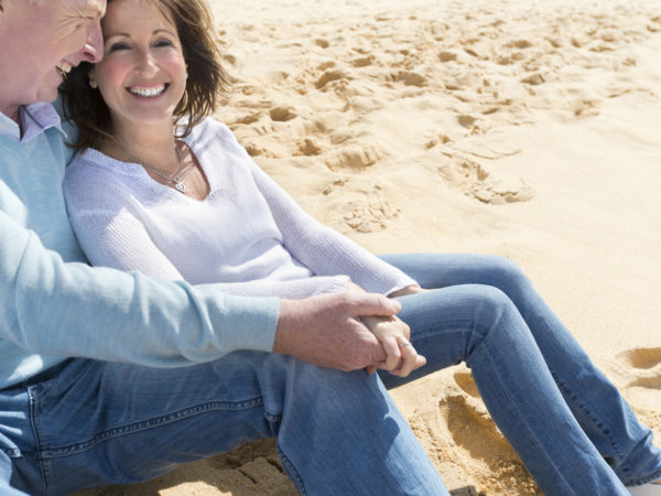 幸福成熟的情侣手牵着手坐在沙滩上