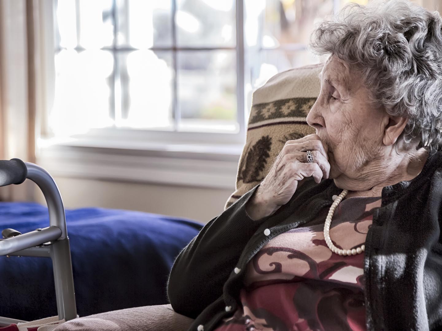 一位老妇人独自坐在一家老年护理机构的画像