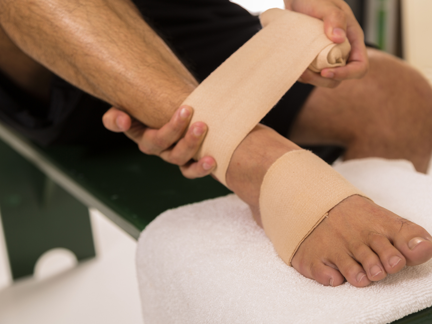 一名男子在体育更衣室包扎疼痛的脚踝。
