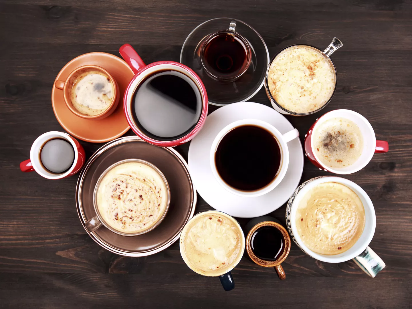 许多不同的咖啡杯在深色的木桌上，俯视。