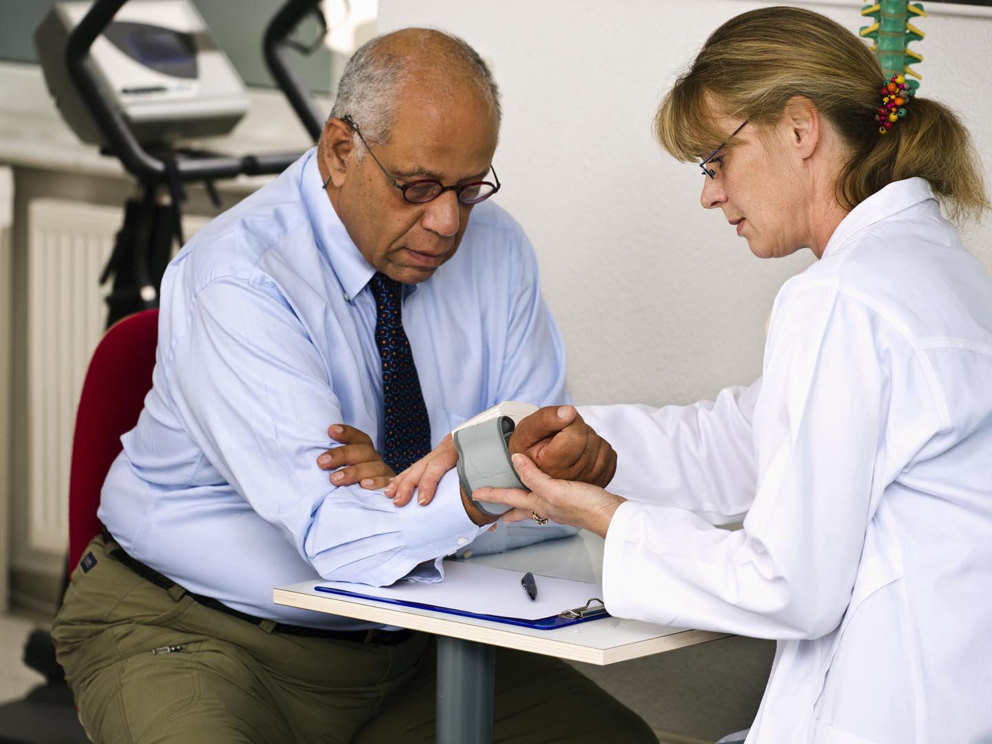 一位成熟的女医生用腕表给她的男病人测量血压。水平。