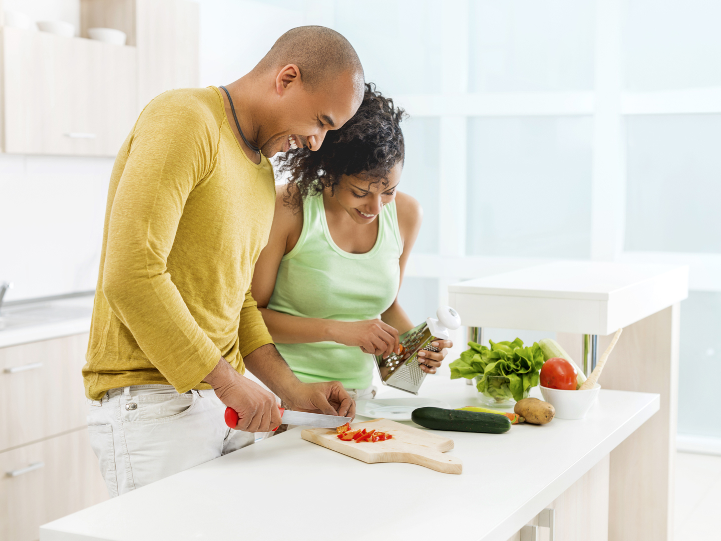 一对微笑的非裔美国夫妇一起在厨房准备食物。