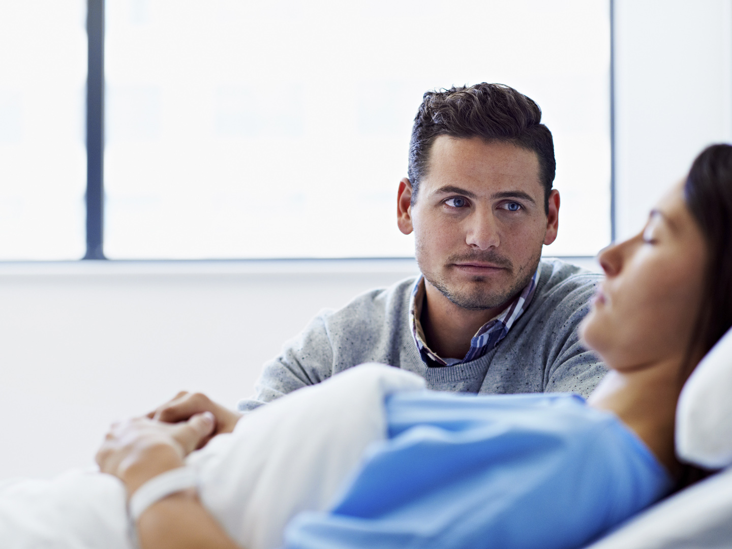 一个女人躺在医院的病床上，她的丈夫在安慰她
