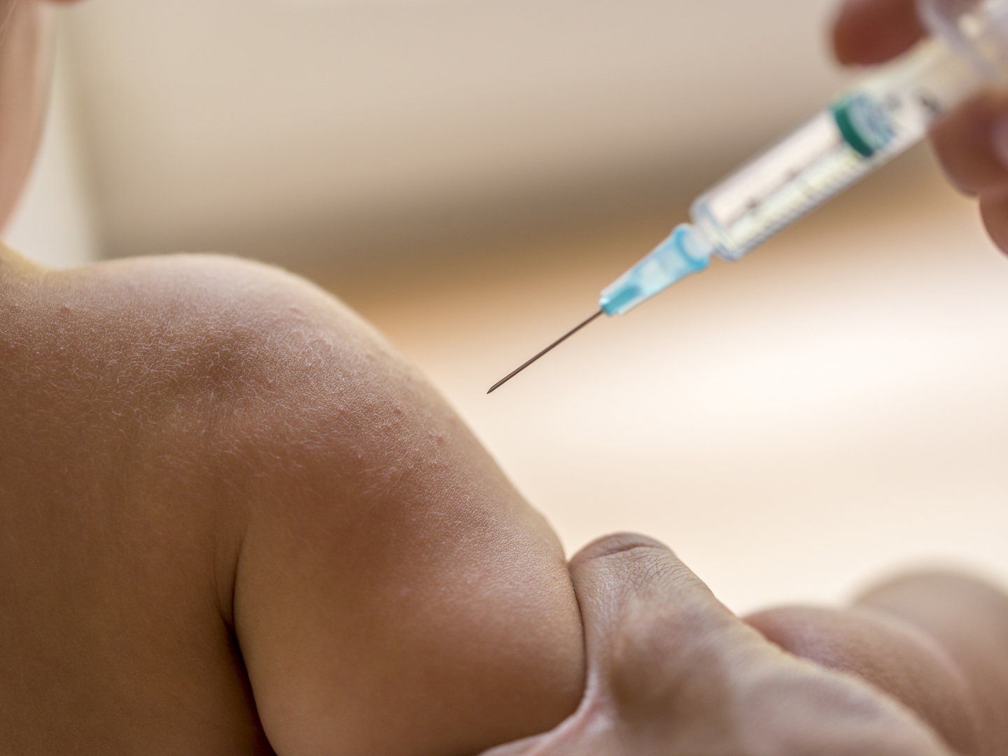 医生用一次性小型皮下注射器给小孩注射疫苗或抗生素，近距离观察孩子的手臂和针头。