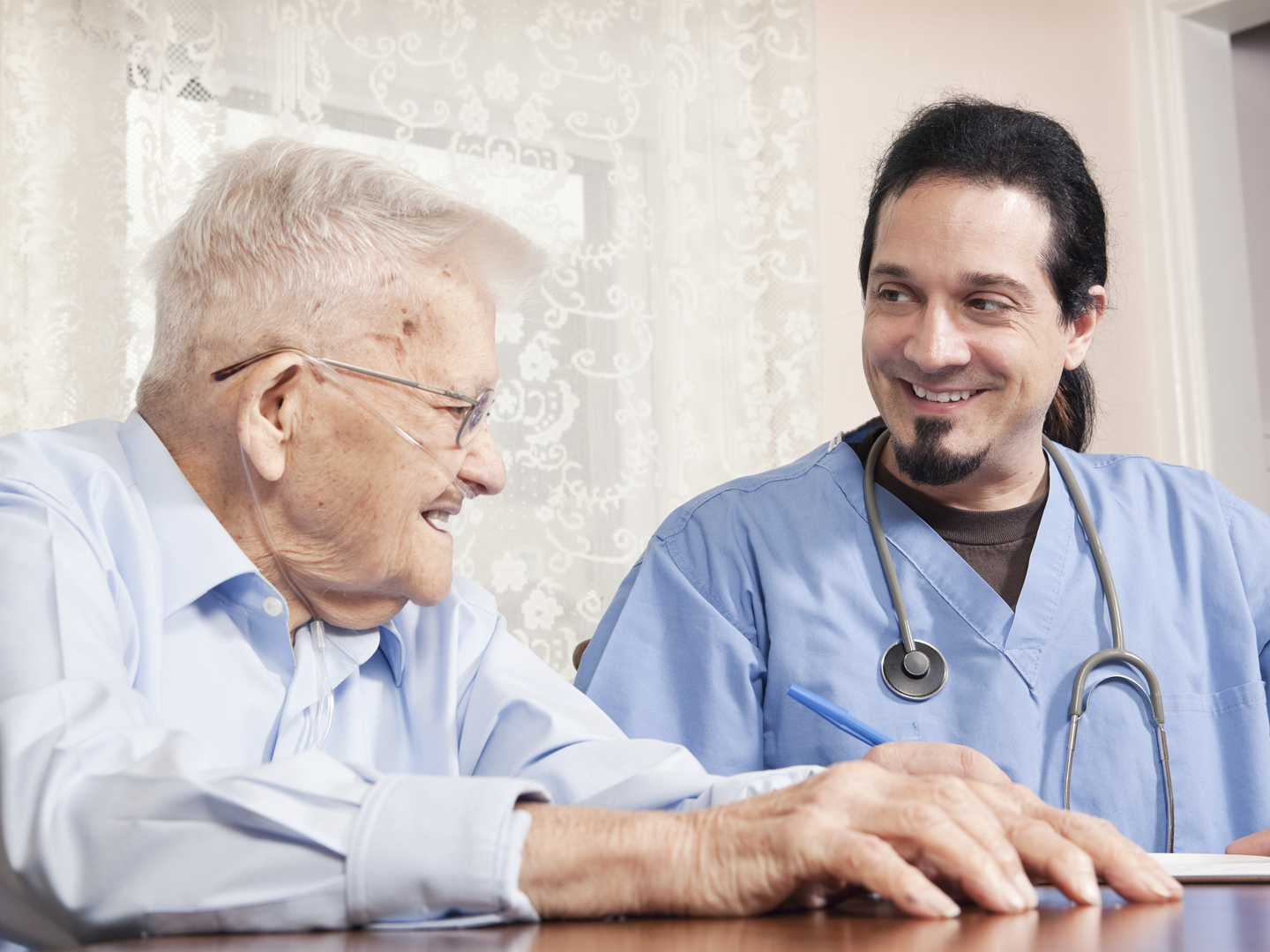 一位家庭保健护士微笑着和他90岁的病人一起看他的病历。