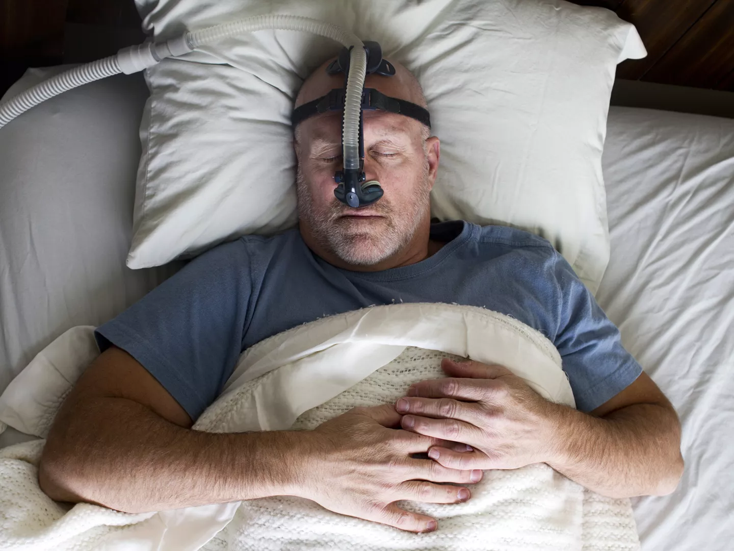 一名男子戴着CPAP口罩睡觉的照片。