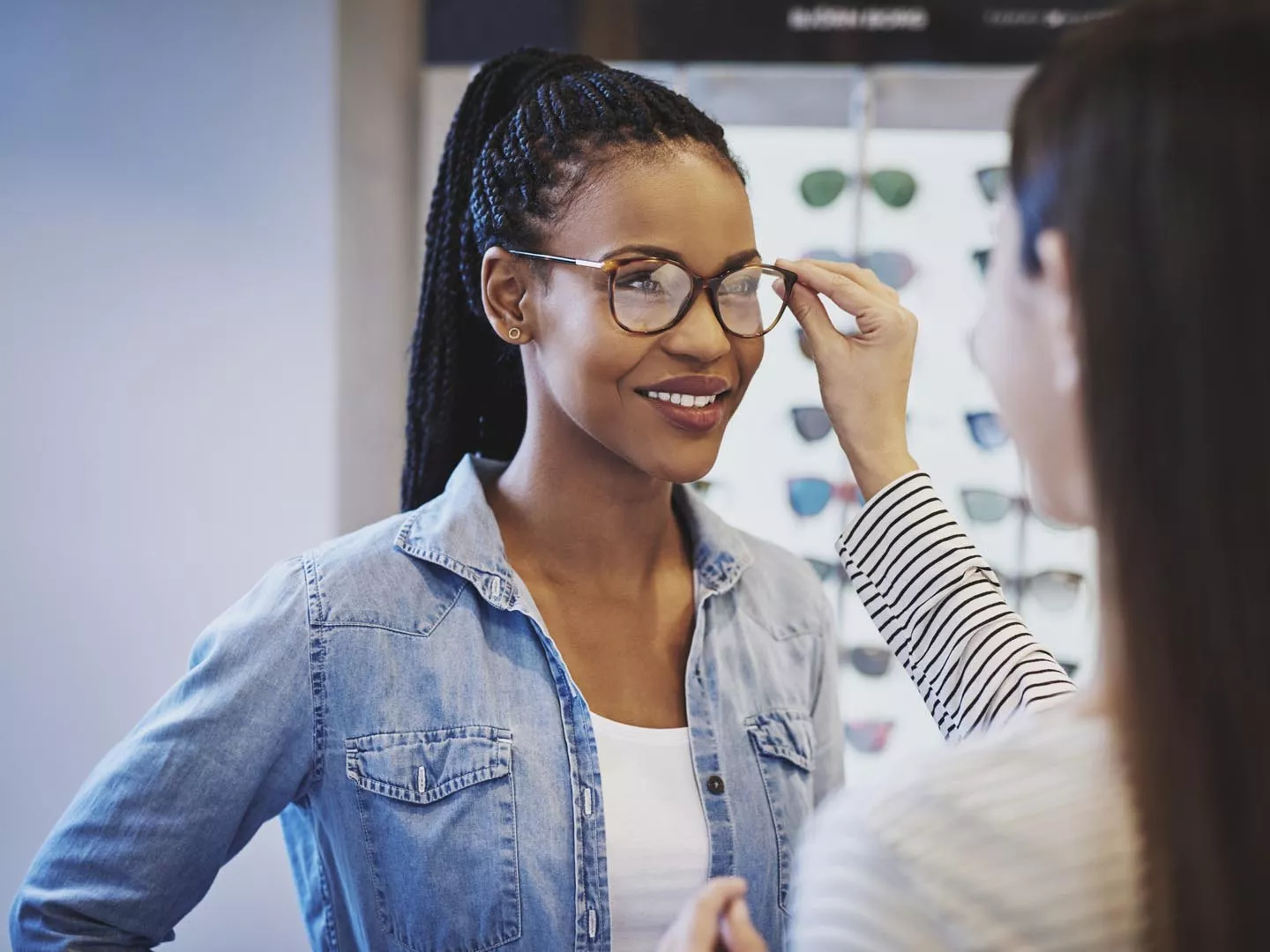 在一家商店里，验光师给一位迷人的非裔美国女性顾客配眼镜，她正在挑选镜框