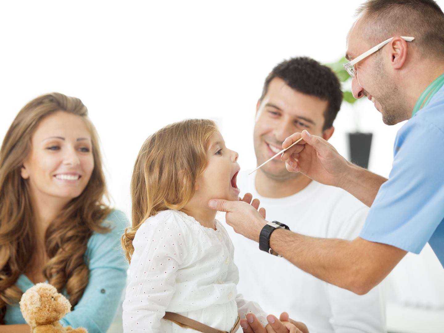快乐的家庭和小女孩在医生办公室。医生检查女孩喉咙痛。父亲抱着小女孩检查。