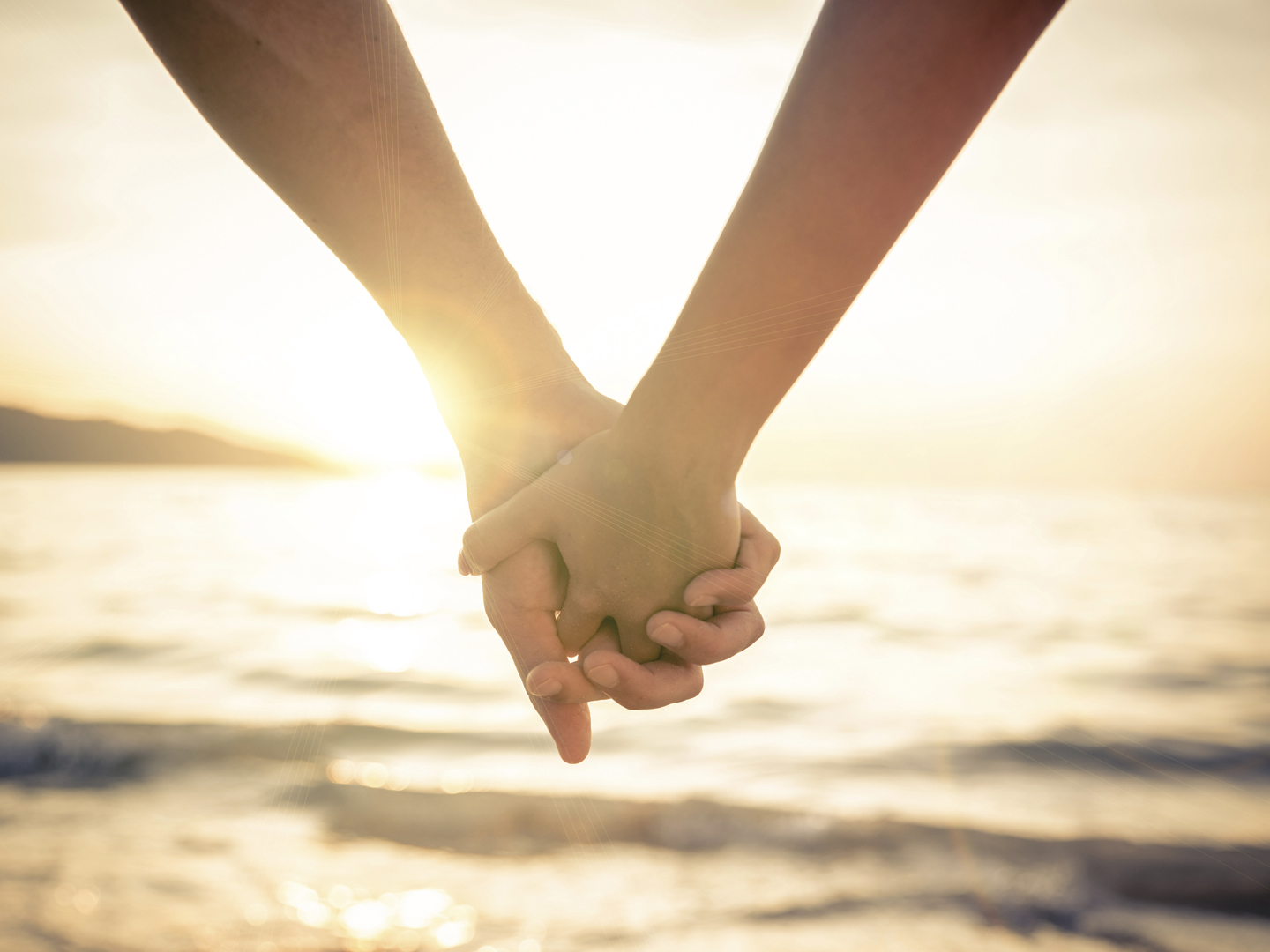 一对情侣牵着他们的手在美丽的日落在海上-新婚夫妇在一个浪漫的假期