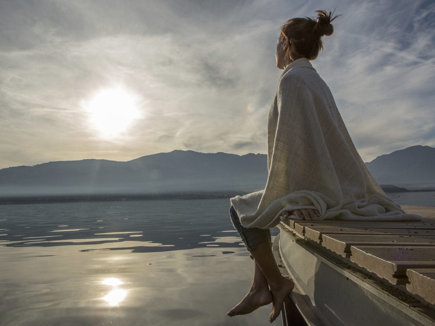 年轻女子在湖码头上休息，看日落。意大利美丽的秋日。