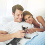 一对年轻夫妇和小猫在卧室里放松的剪影