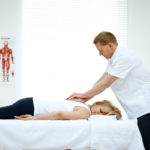 男性骨科医生治疗背部问题的一个女人躺在医疗室